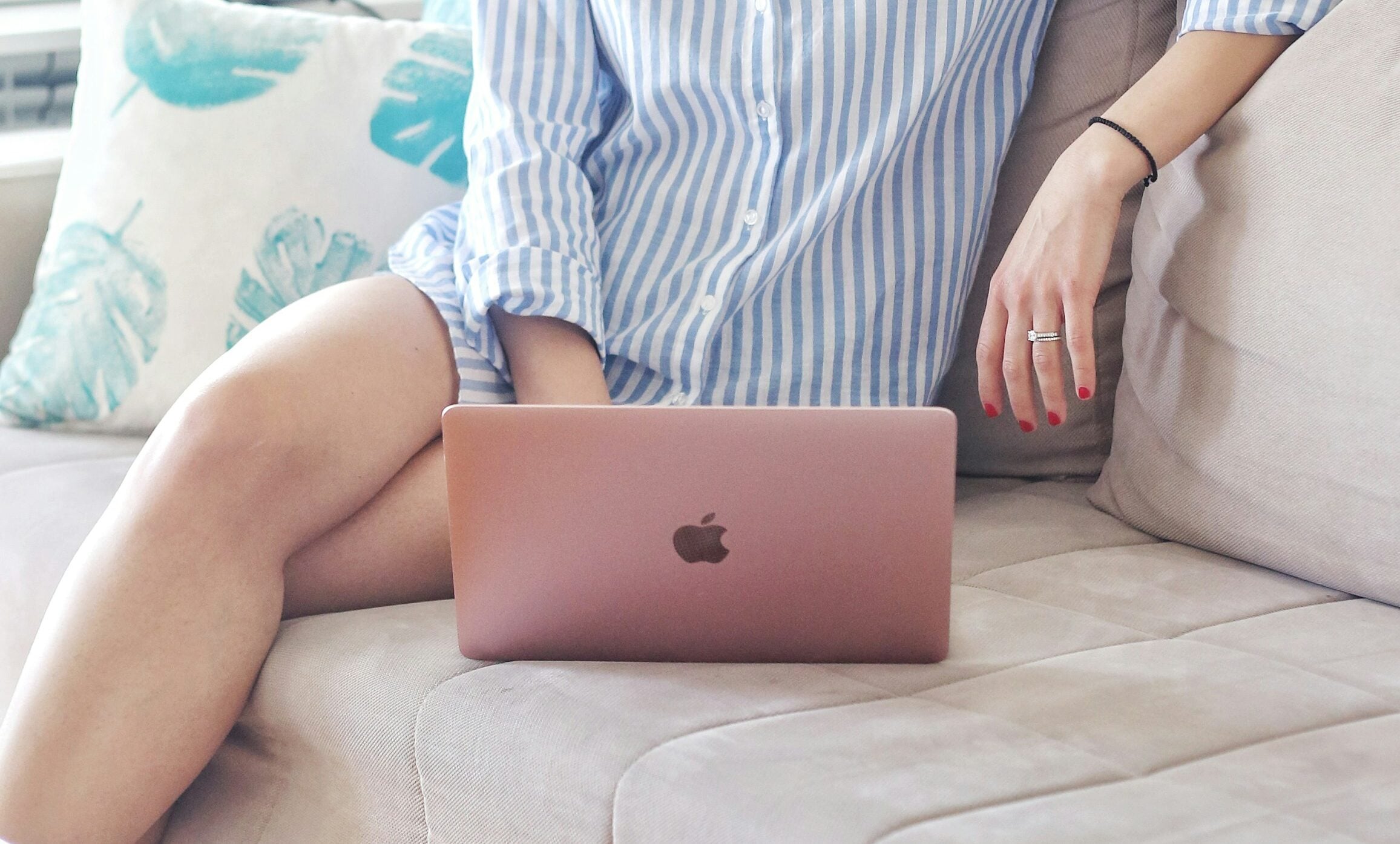 A woman sitting with her laptop on the couch cushion.