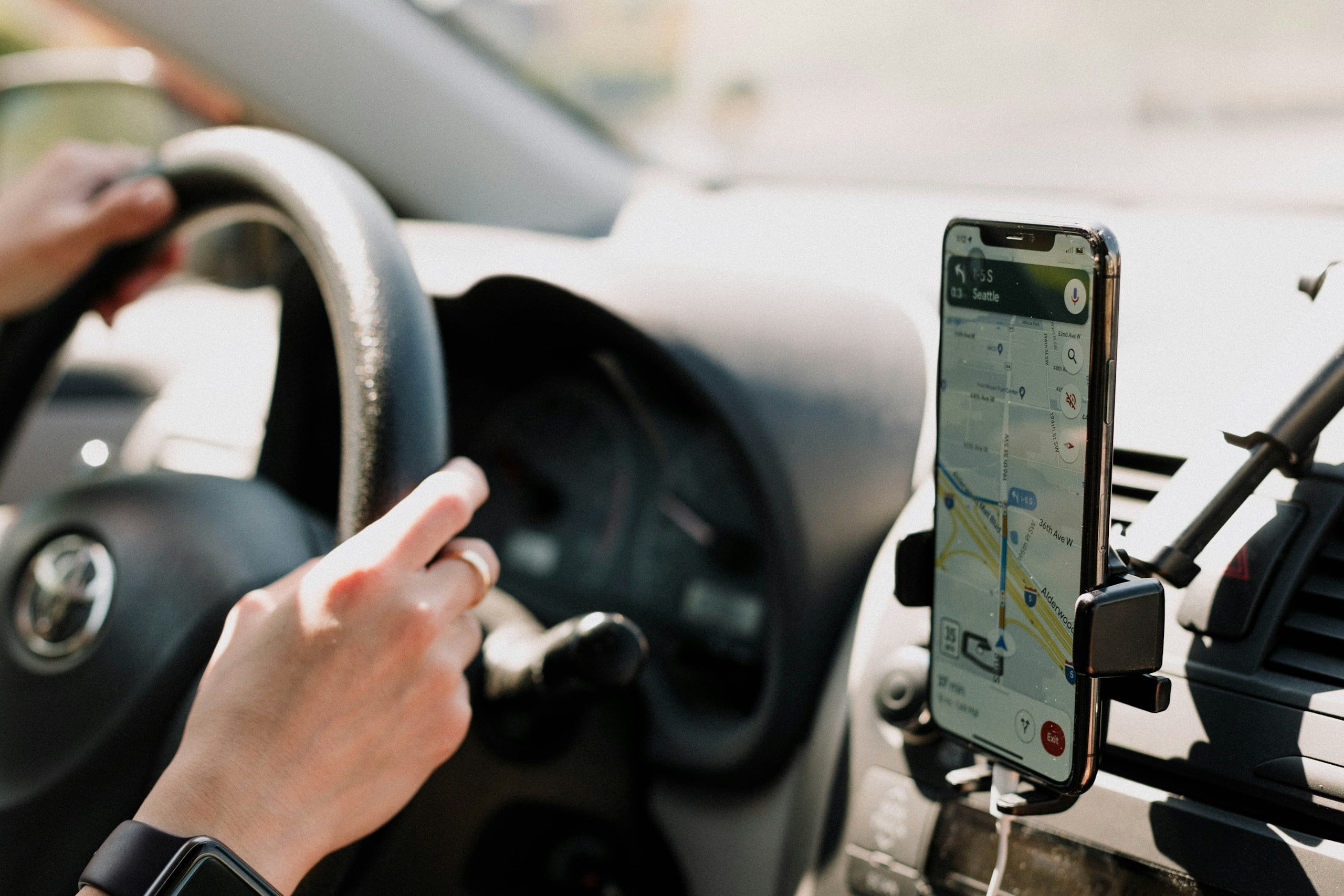 Person using GPS on smartphone while driving a car. 