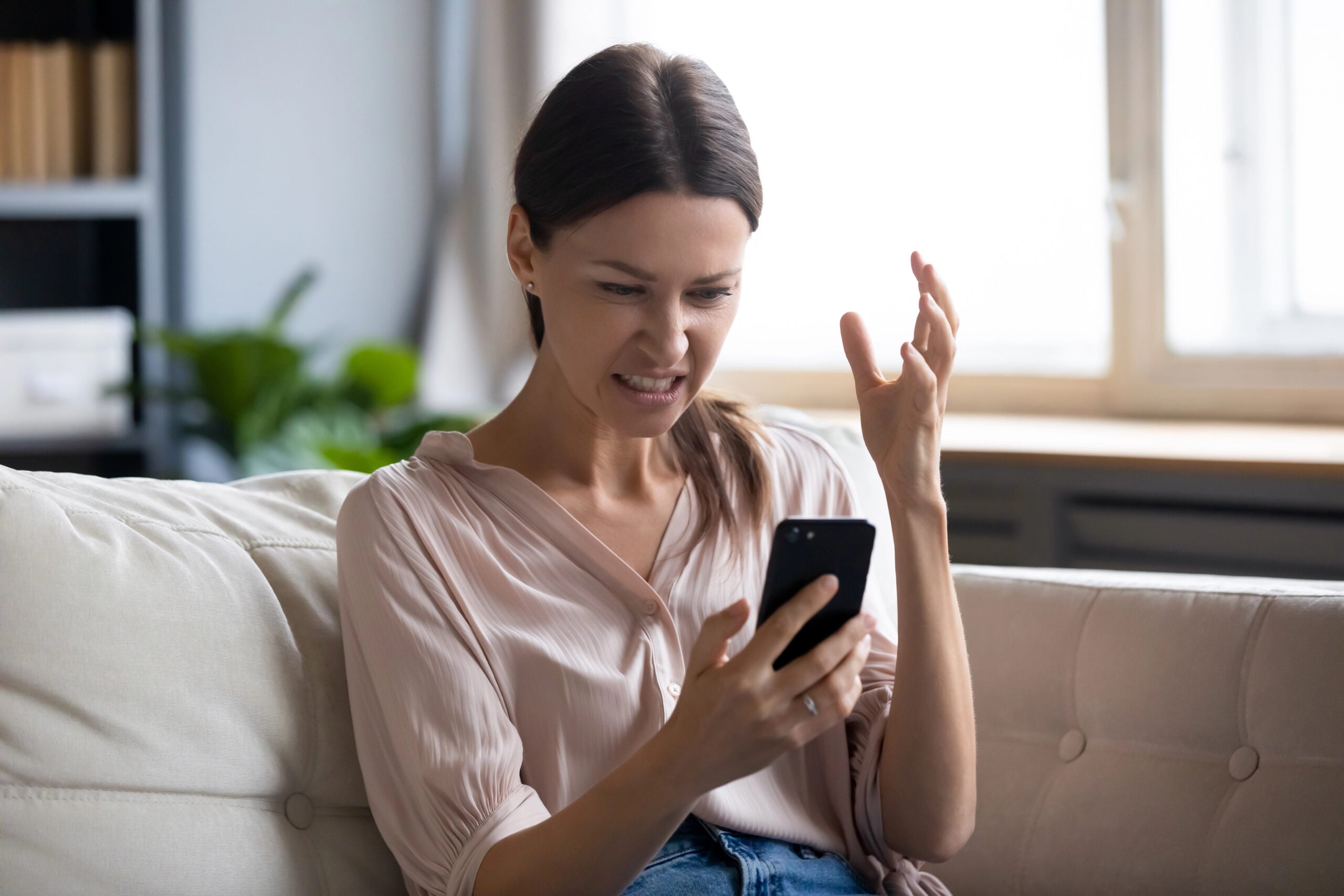 Annoyed young woman looking at mobile phone screen.