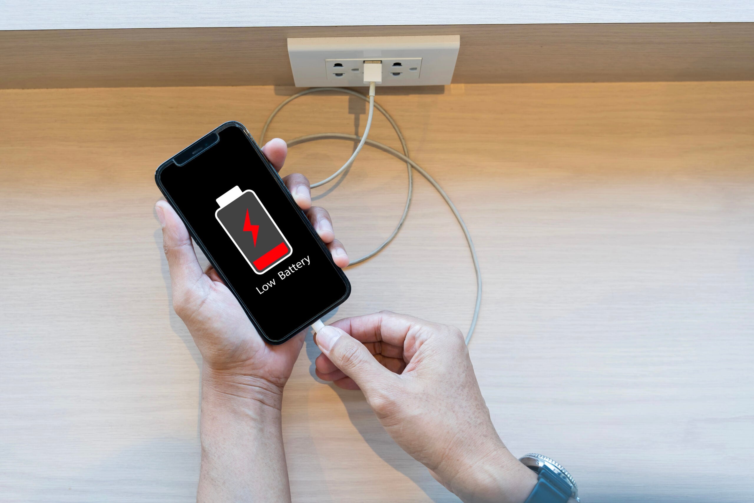 Close up man's hands using smart phone battery low charge battery screen, Businessman holding a smartphone  Low battery warning on a mobile phone. Need to connect the charger to the smartphone icon