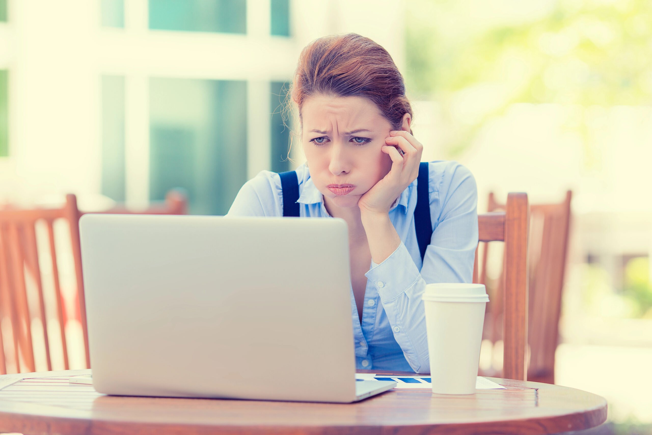 displeased worried business woman sitting in front of laptop computer