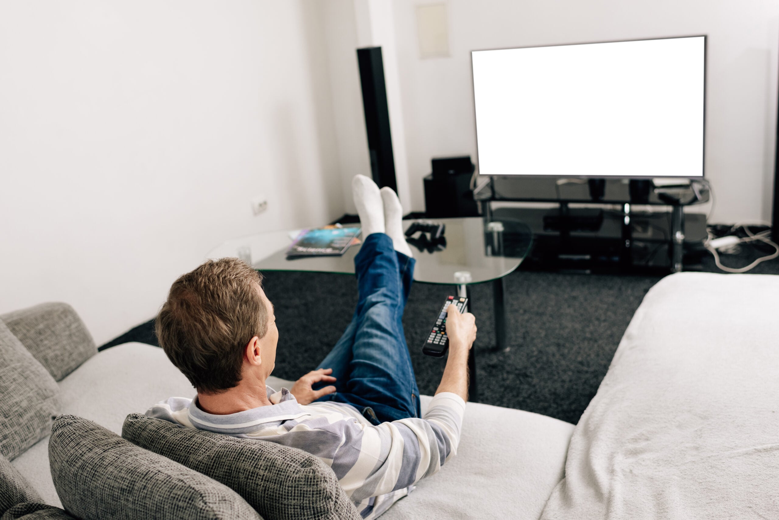 man in jeans holding remote controller near white tv screen at home
