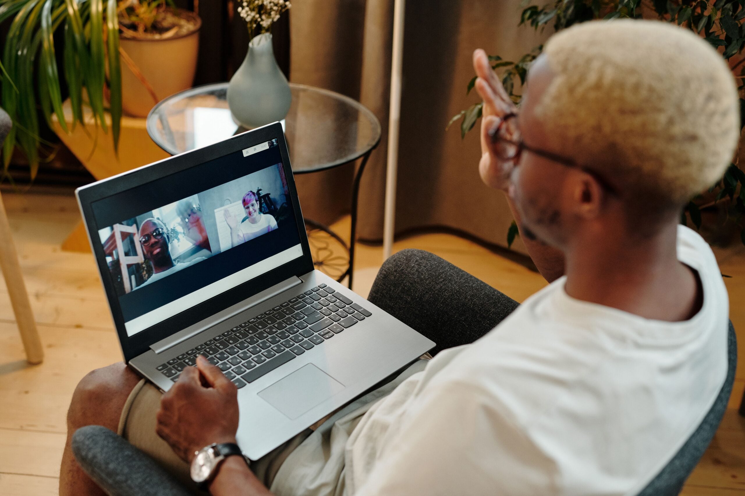 Man video calling using a laptop while sitting on a chair