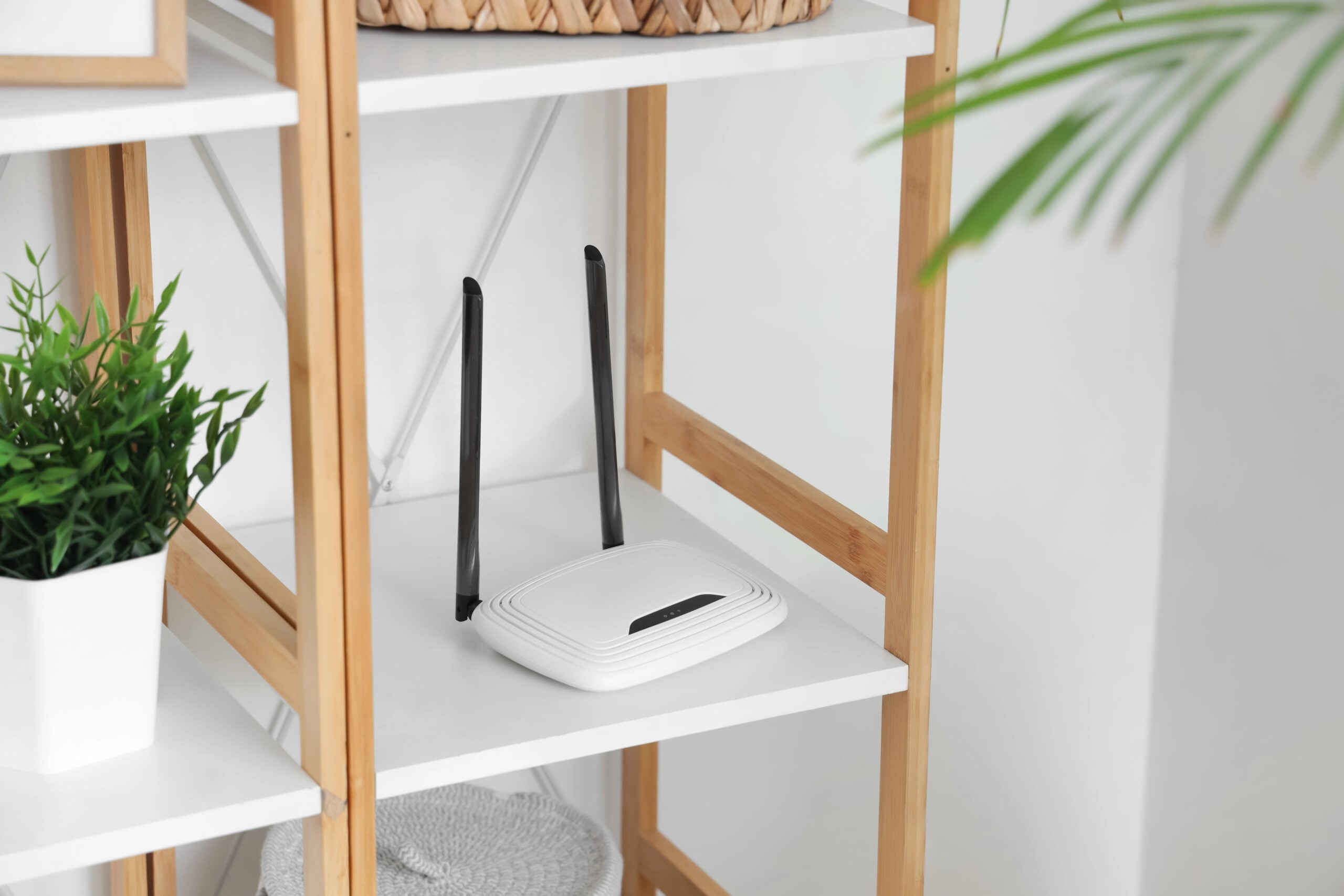 Modern wi-fi router on shelf near light wall, closeup