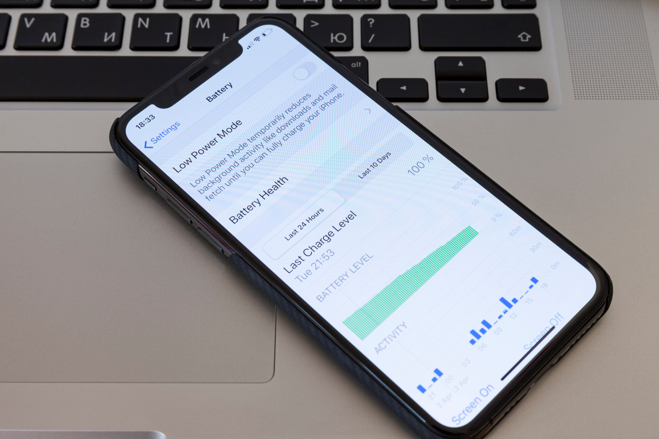 MOSCOW / RUSSIA - APRIL 4, 2020: iPhone 11 Pro lies on a MacBook keyboard. On the menu screen for setting the battery saver mode