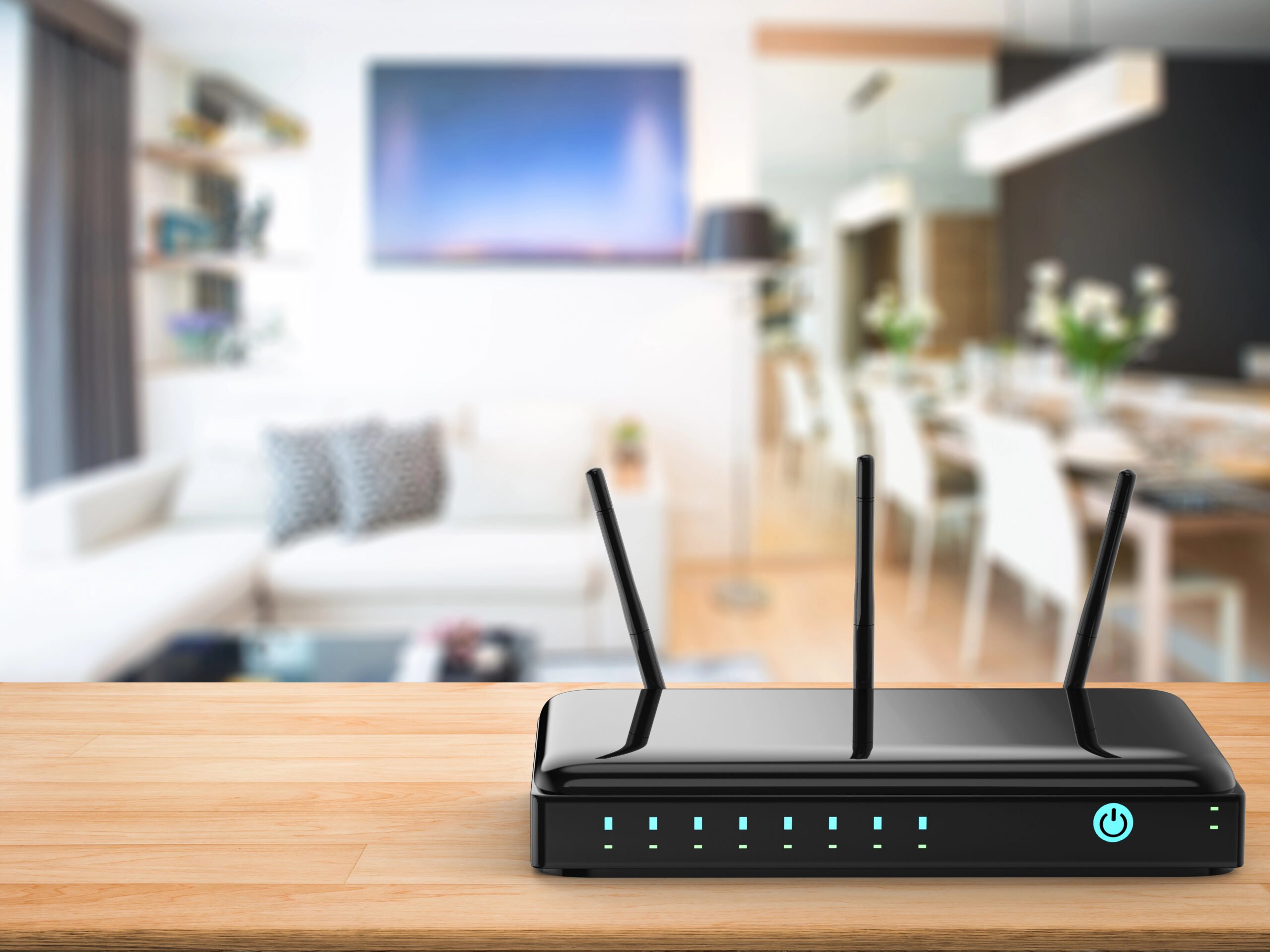 A black router sitting on a wooden table out in the open in a living room.