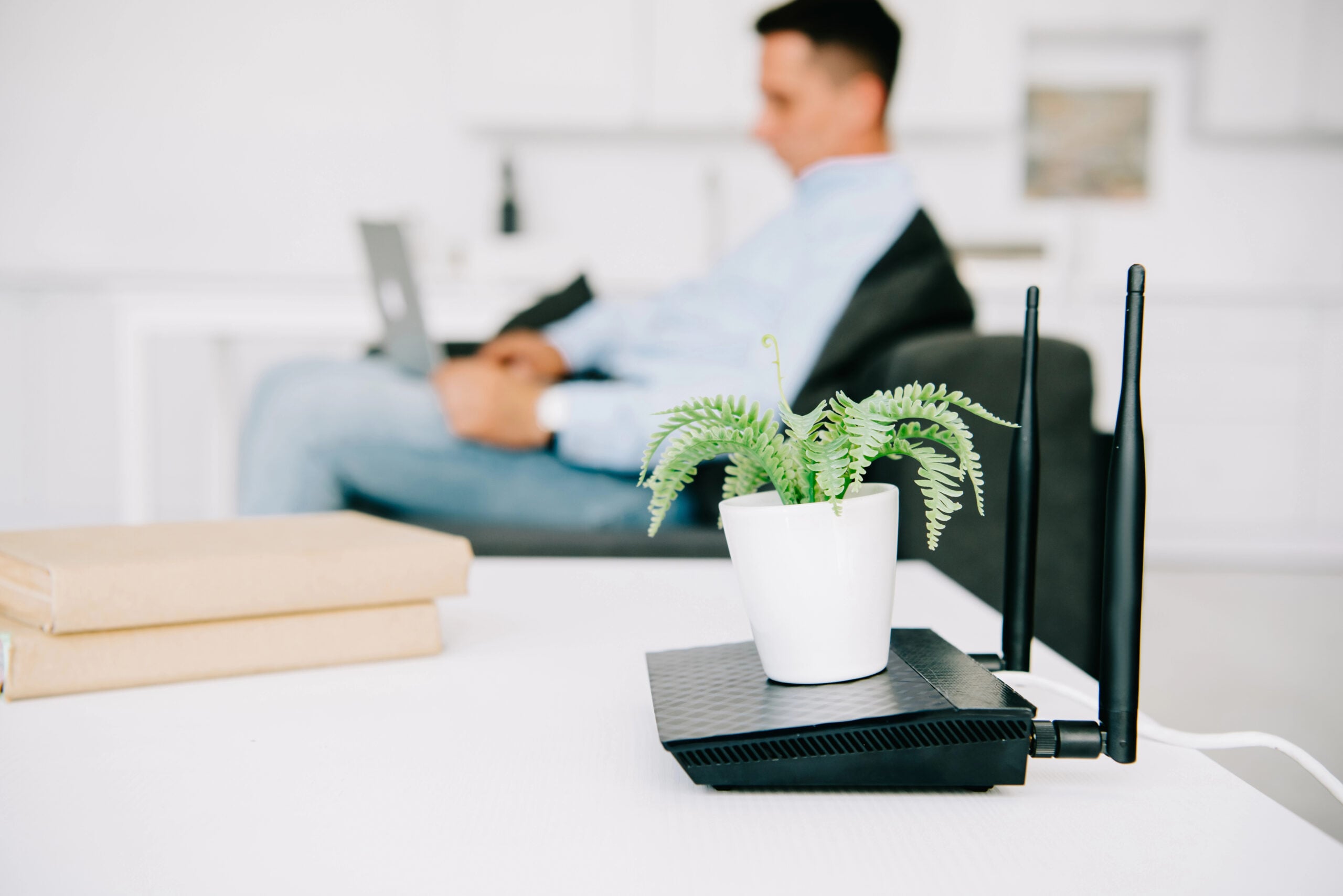 selective focus of flowerpot on black router and businessman using laptop
