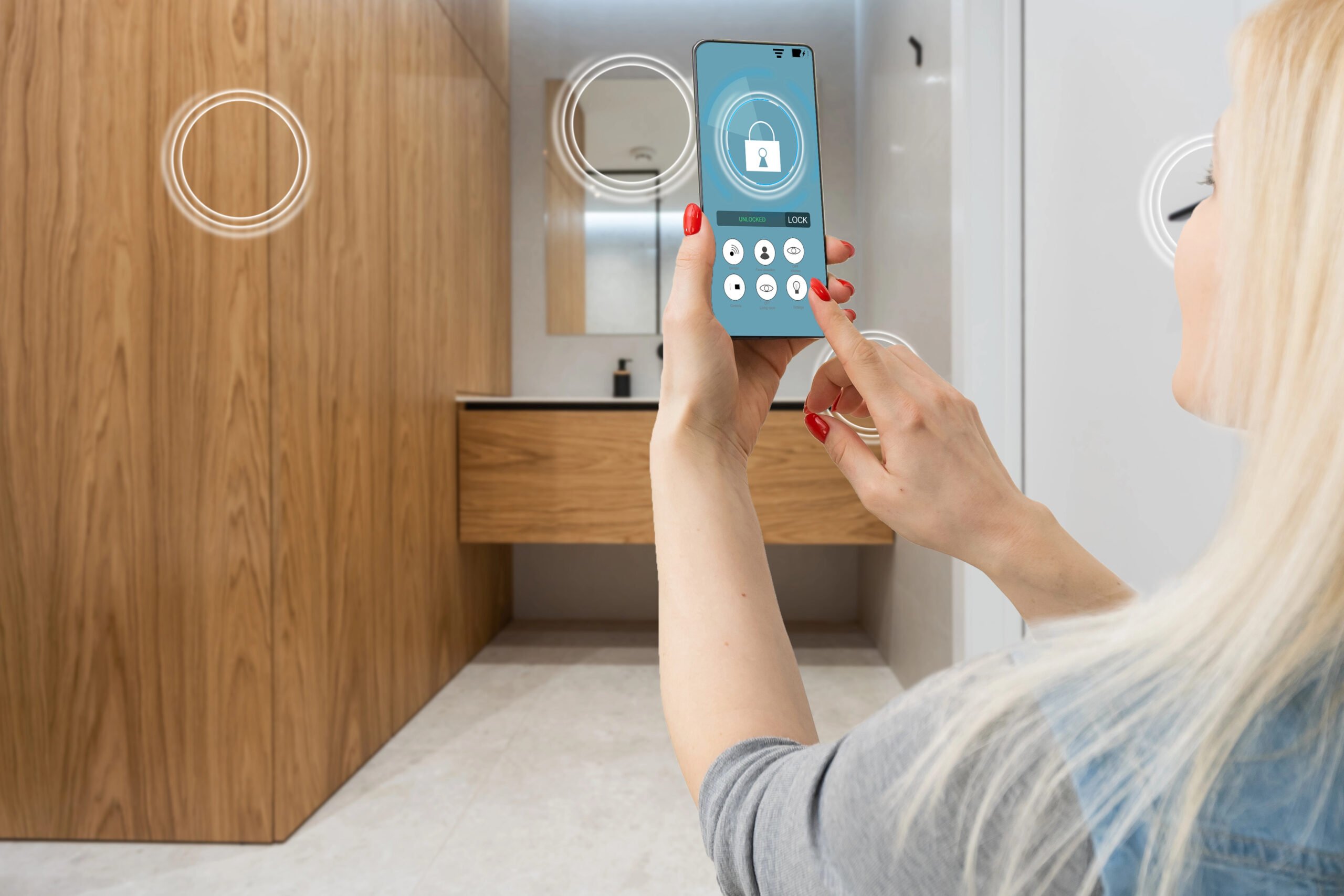 Smart home automation app on smartphone hold by female hand with home interior in background.