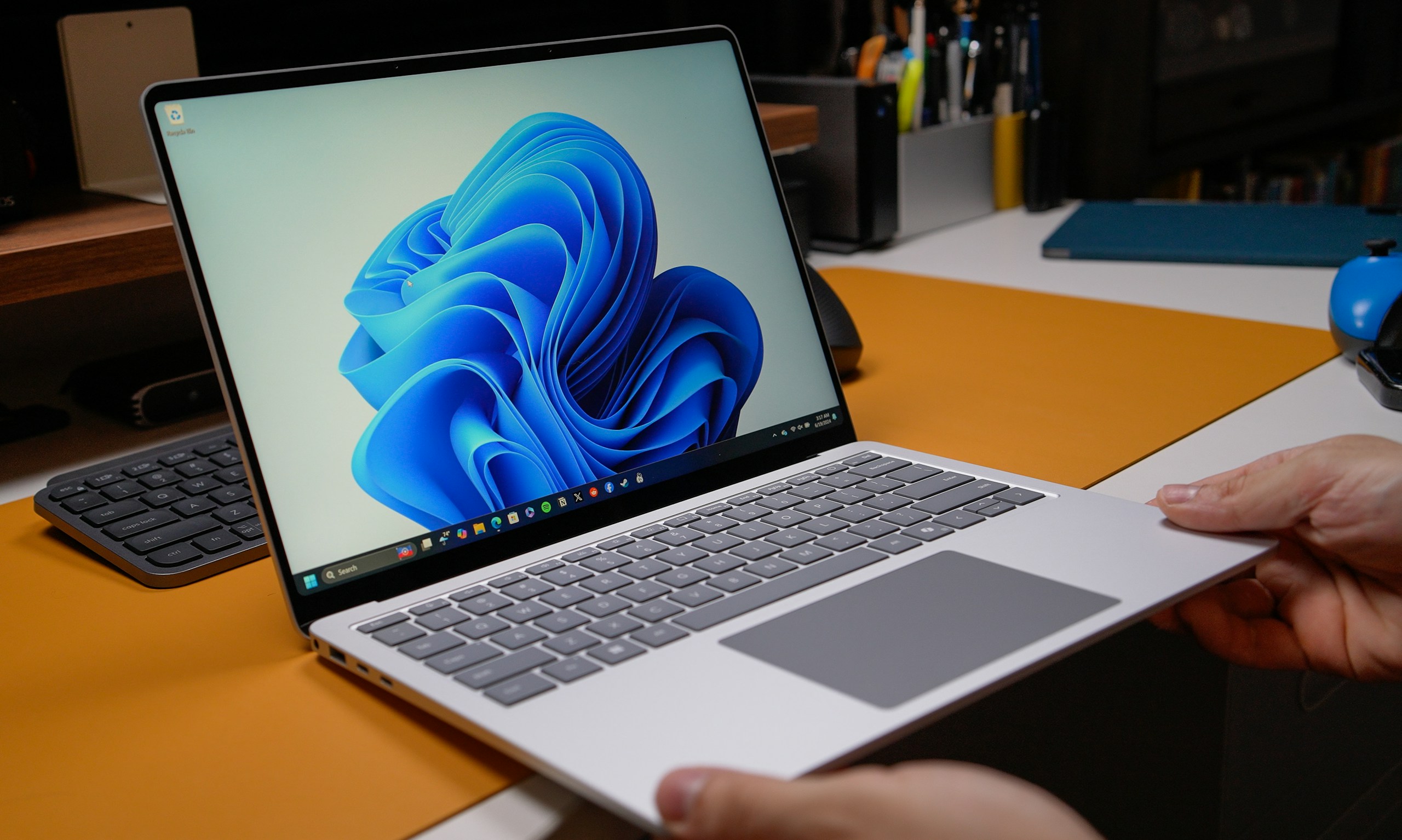Windows laptop open on modern desk with blue wallpaper