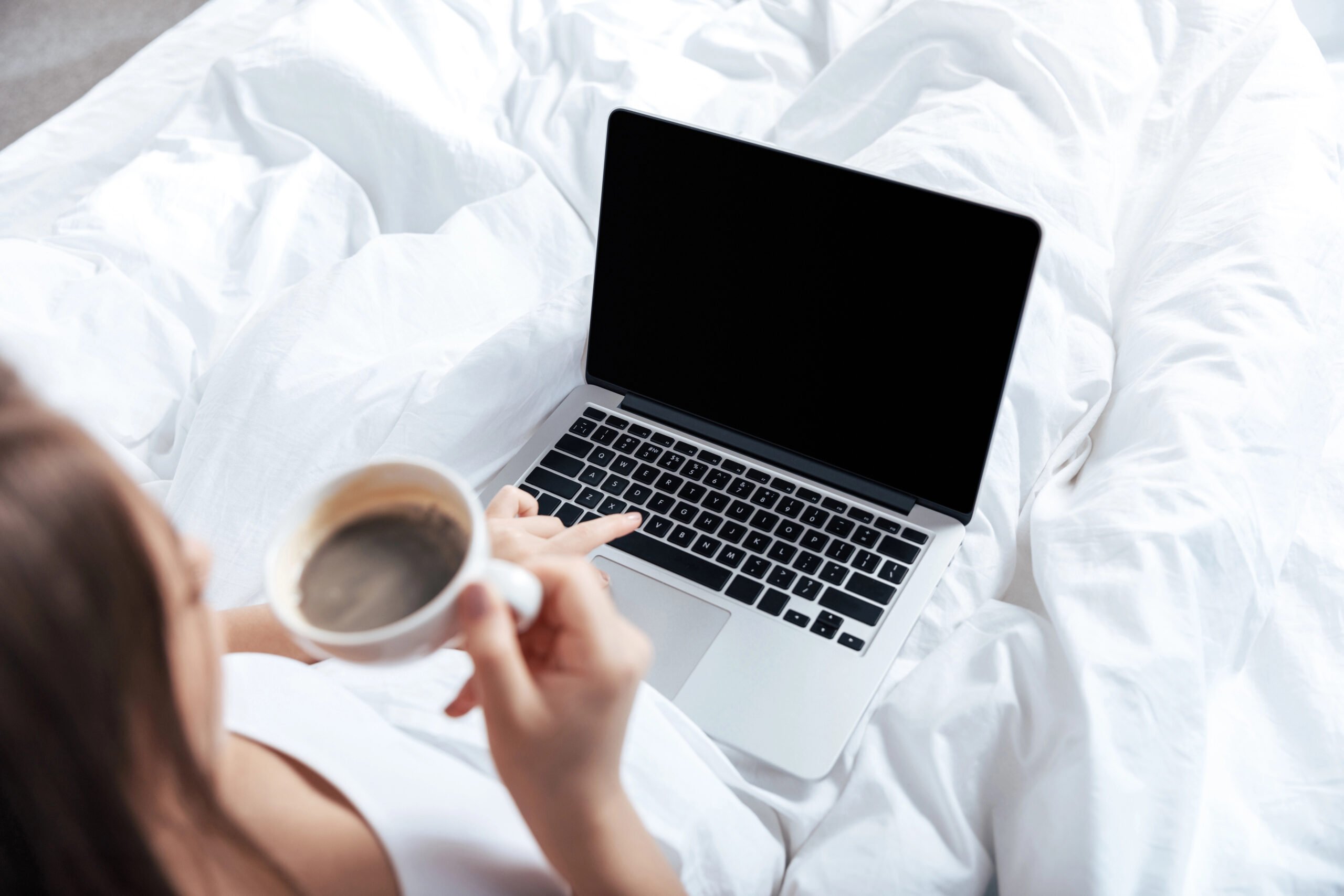 woman working on laptop in bed