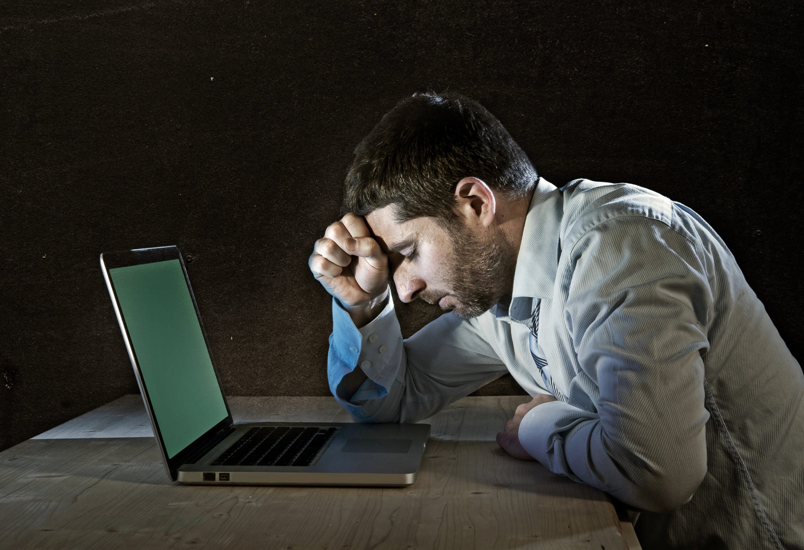 Young stressed businessman working on desk with computer laptop in frustration and depression